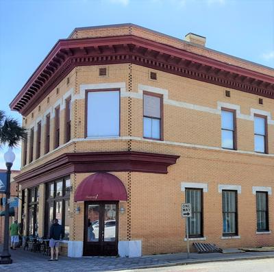 Corner two-story building in Orange-yellow brick with reddish awning and trim with lots of windows